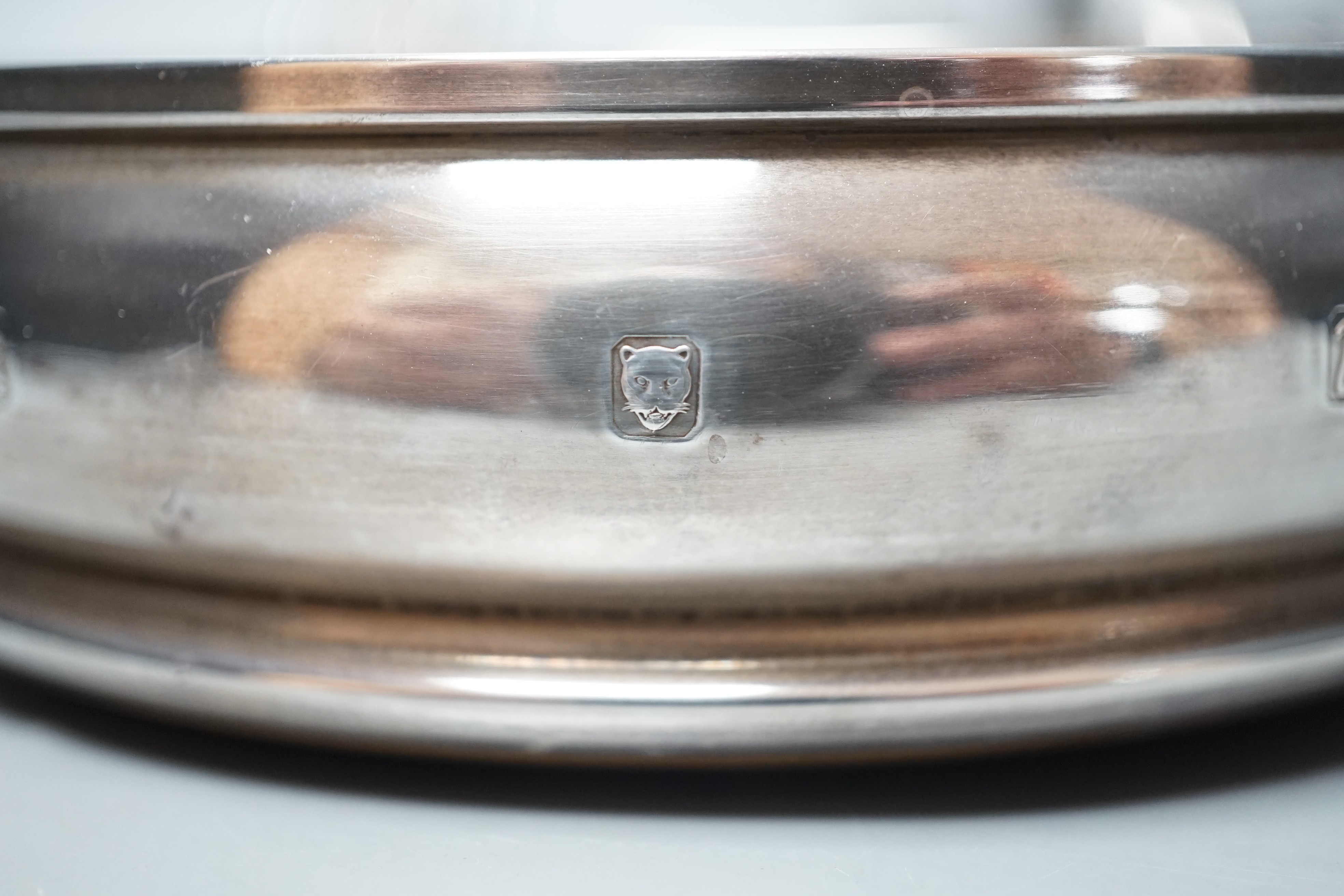 A modern silver mounted wine coaster, London, 1996, diameter 12.4cm, an earlier pierced silver bonbon dish and a pair of plated candlesticks.